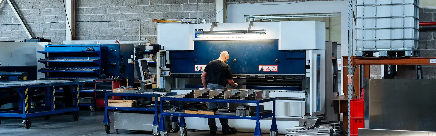 Industrial workshop featuring CNC machining press brake operation, with skilled technician performing precision metal bending and fabrication process