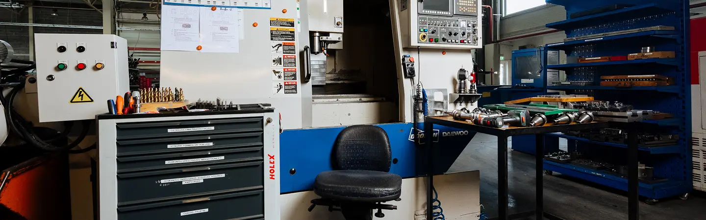 CNC machining workstation with precision tooling, control panel, and organized workshop setup, illustrating the meticulous environment of advanced metal fabrication